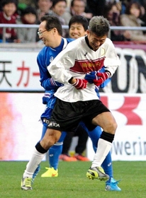 阪神・淡路大震災20年のチャリティーサッカーで、後半、選手として出場した元日本代表監督の岡田武史さんに抱きつかれる横浜ＦＣの三浦知良（右）＝２０１５年１月17日、ノエビアスタジアム神戸