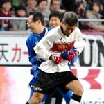 阪神・淡路大震災20年のチャリティーサッカーで、後半、選手として出場した元日本代表監督の岡田武史さんに抱きつかれる横浜ＦＣの三浦知良（右）＝２０１５年１月17日、ノエビアスタジアム神戸