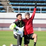 トレーニングの合間、Ｇ大阪の井手口陽介とカメラに向かって笑顔でポーズを取る横浜ＦＣの三浦知良＝１５日午前、大阪府内