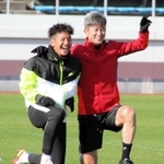 トレーニングの合間、Ｇ大阪の井手口陽介とカメラに向かって笑顔でポーズを取る横浜ＦＣの三浦知良＝１５日午前、大阪府内