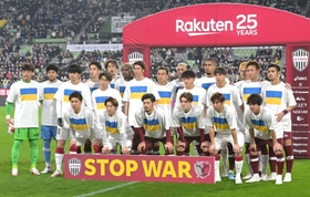 試合前、ウクライナ国旗があしらわれたＴシャツを着て入場し、記念撮影に臨むヴィッセル神戸、鹿島アントラーズの選手たち＝１１日夜、ノエビアスタジアム神戸（撮影・秋山亮太）