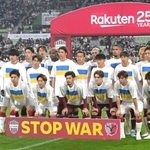 試合前、ウクライナ国旗があしらわれたＴシャツを着て入場し、記念撮影に臨むヴィッセル神戸、鹿島アントラーズの選手たち＝１１日夜、ノエビアスタジアム神戸（撮影・秋山亮太）