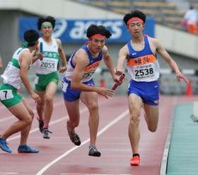 高校男子１６００メートルリレー決勝　３走富山涼太からバトンを受けて駆け出す姫路のアンカー高見陸亜（中央）＝ユニバー記念競技場（撮影・小林良多）