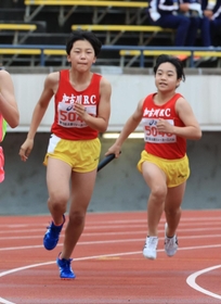 小学女子４００メートルリレー決勝　加古川ＲＣの３走納庄晴夏（右）がアンカー藤原瞭希にバトンをつなぐ＝ユニバー記念競技場（撮影・吉田敦史）