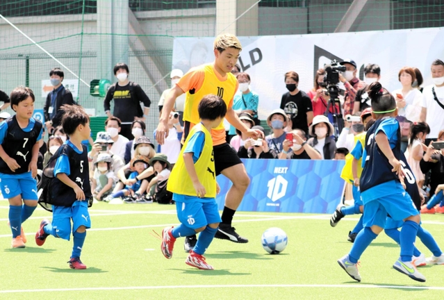 子どもたちに囲まれながらドリブルを仕掛ける堂安律＝尼崎市、ＲＤフィールド
