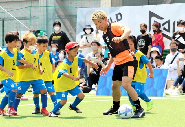 子どもたちに囲まれながらボールをキープする堂安律＝尼崎市、ＲＤフィールド