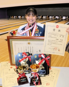 小中高の全国大会や国際大会で贈られた賞状やメダルを手にするボウリング女子の石田万音＝神戸市中央区、ラウンドワン三宮駅前店