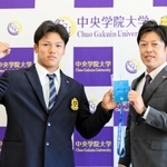 ヤクルトの担当スカウトから指名挨拶を受けた橋本星哉（左）。高津臣吾監督直筆の「一緒に頑張ろう」のメッセージを受け取った＝２６日午後、千葉県我孫子市の中央学院大（大学提供）