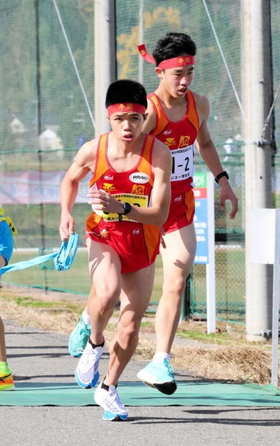 男子・平岡　２区村上大佑（右）からたすきを受けて駆け出す３区新妻昂己＝豊岡市日高町（撮影・長嶺麻子）
