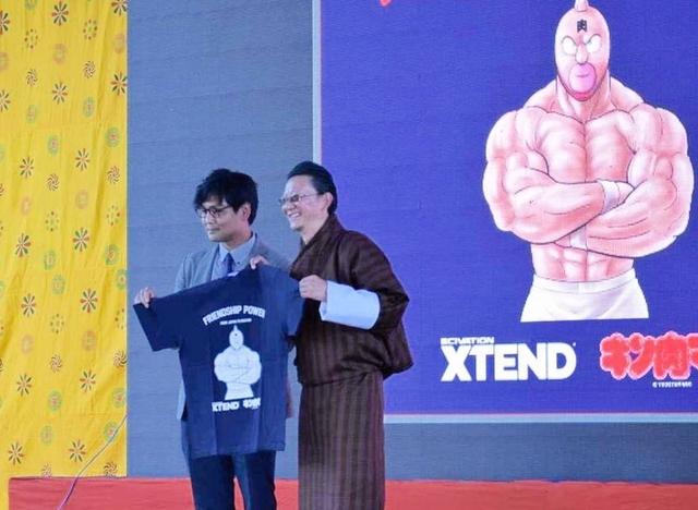 キン肉マンとのコラボレーションＴシャツを持つ山崎道洋さん（左）とブータン柔道協会のカルマ・ドルジ会長＝ブータン・ティンプー（ブータン柔道協会提供）
