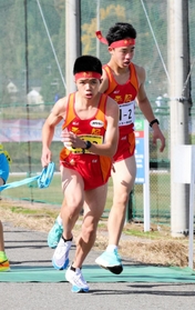 男子・平岡　２区村上大佑（右）からたすきを受けて駆け出す３区新妻昂己＝豊岡市日高町（撮影・長嶺麻子）