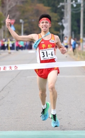 初優勝を飾り、笑顔でフィニッシュする男子・平岡のアンカー新妻遼己＝１９日、豊岡市日高町（撮影・長嶺麻子）
