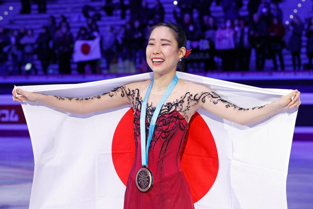 フィギュアスケート・ＧＰファイナルの女子で初出場優勝を果たし、日の丸を広げる三原舞依＝10日、イタリア・トリノ（共同）