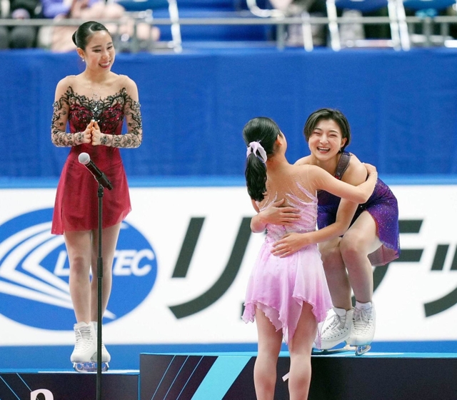 女子で優勝し、表彰式で島田麻央（手前）と抱き合う坂本花織。左は三原舞依＝24日、東和薬品ラクタブドーム