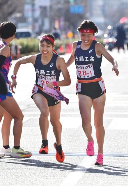 女子・西脇工の１区塩崎彩理（右）からたすきを受け走りだす２区飯塚菜月（撮影・中西幸大）