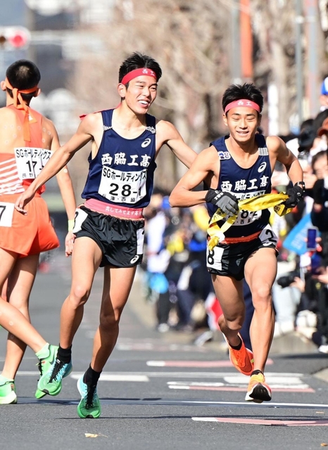 男子１区で区間賞に輝いた西脇工の長嶋幸宝（左）から２区小田伊織へたすきリレー＝京都市内