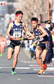 男子１区で区間賞に輝いた西脇工の長嶋幸宝（左）からたすきを受ける２区小田伊織＝２５日午後、京都市内