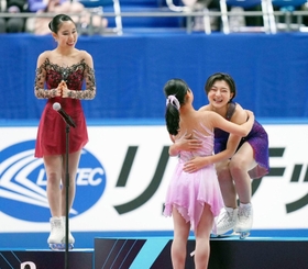 女子で優勝し、表彰式で島田麻央（手前）と抱き合う坂本花織。左は三原舞依＝24日、東和薬品ラクタブドーム