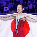 フィギュアスケート・ＧＰファイナルの女子で初出場優勝を果たし、日の丸を広げる三原舞依＝10日、イタリア・トリノ（共同）