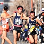 男子１区区間賞に輝いた西脇工の長嶋幸宝（左）から２区小田伊織へたすきリレー＝京都市内