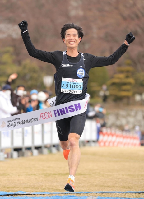 大会新記録で初優勝、両手を挙げてフィニッシュする秋山雄飛＝２６日午前、姫路市