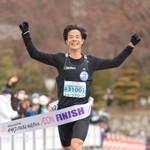 大会新記録で初優勝、両手を挙げてフィニッシュする秋山雄飛＝２６日午前、姫路市