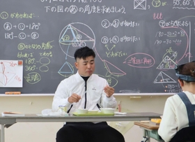 児童たちと給食を食べる蟬川泰果（中央）。感染対策のため黙食した＝兵庫教育大付属小