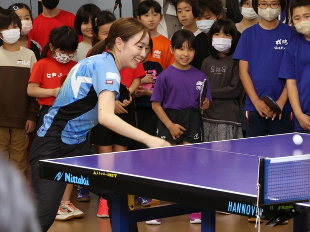 子どもたちが見守る中でラリーを続ける石川選手＝神戸市長田区二葉町５、卓球場「Ｋｕｎｉｚｕｋａ　ＴＡＱ」