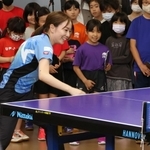 子どもたちが見守る中でラリーを続ける石川選手＝神戸市長田区二葉町５、卓球場「Ｋｕｎｉｚｕｋａ　ＴＡＱ」