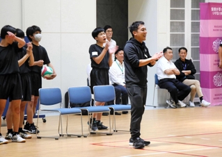 バレーボールの試合中に笑顔で選手をたたえる指導者（中央）＝神戸市中央区