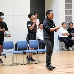 バレーボールの試合中に笑顔で選手をたたえる指導者（中央）＝神戸市中央区