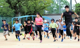 クラブ研修を兼ねた陸上教室。子どもたちと一緒に走る実習生の三平紫衣さん（中央）と稲沢佑真さん（右から２人目）＝明石市明南町３、沢池小学校
