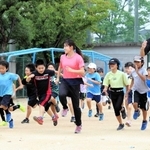 クラブ研修を兼ねた陸上教室。子どもたちと一緒に走る実習生の三平紫衣さん（中央）と稲沢佑真さん（右から２人目）＝明石市明南町３、沢池小学校