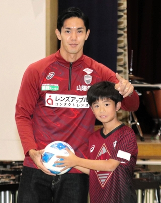 贈呈したボールを手に明親小の６年生と記念撮影に納まる神戸のＦＷ武藤嘉紀＝神戸市兵庫区須佐野通４の同校