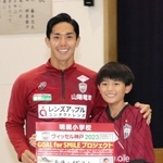 メッセージボードを手に明親小の６年生と記念撮影に納まる神戸のＦＷ武藤嘉紀＝神戸市兵庫区須佐野通４の同校