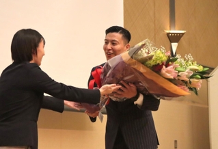 引退セレモニーで板橋美波（左）から花束を受け取る寺内健さん＝尼崎市内のホテル