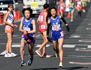 兵庫の２区・田中希実（右）からたすきを受け取り走り出す３区・藤田莉沙＝１４日午後、京都市上京区の第２中継所