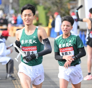 植月俊太（右）からたすきを受け取り、７区へ走り出す東農大・前田和摩＝小田原中継所（撮影・伊藤笙子）