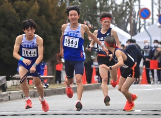 男子・須磨学園の３区堀野正太（左から２人目）が４区梅本陸翔へたすきをつなぐ。後ろは西脇工Ａ