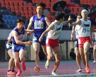 バトンをつなぐ滝川第二と社の選手たち＝ユニバー記念競技場（撮影・笠原次郎）