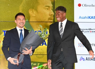 引退会見でシントトロイデンで同僚だったＧＫ鈴木彩艶（右）から花束を受け取り、笑顔の岡崎慎司さん＝２０２４年６月、東京都内