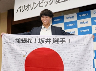 メッセージ入り日の丸とともに笑顔を見せる坂井隆一郎＝大阪市の大阪ガス本社