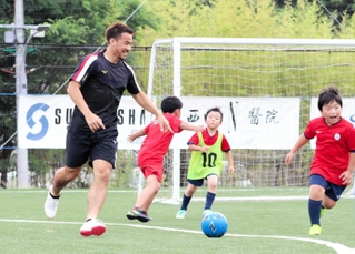 環境配慮型グラウンドで子どもたちと交流する岡崎慎司さん。地域貢献と青少年の育成もサッカー人生第２幕の目標だ＝２０２２年６月、神戸市西区のバサラヴィレッジグリーン