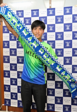 Ｊ１湘南入りが内定し、ユニホームに身を包んでチームタオルを掲げる神戸弘陵高の石橋瀬凪＝神戸市北区、同高