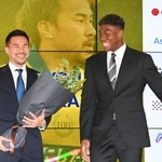 引退会見でシントトロイデンで同僚だったＧＫ鈴木彩艶（右）から花束を受け取り、笑顔の岡崎慎司さん＝２０２４年６月、東京都内