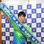 Ｊ１湘南入りが内定し、ユニホームに身を包んでチームタオルを掲げる神戸弘陵高の石橋瀬凪＝神戸市北区、同高