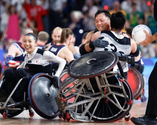 パリ・パラリンピックの車いすラグビーの決勝で、米国を破り金メダルを獲得し橋本（手前）と抱き合って喜ぶ池。左は倉橋＝２日、パリ（共同）