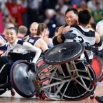 パリ・パラリンピックの車いすラグビーの決勝で、米国を破り金メダルを獲得し橋本（手前）と抱き合って喜ぶ池。左は倉橋＝２日、パリ（共同）