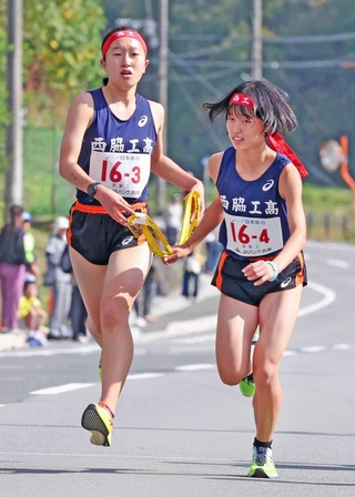 女子・西脇工の３区藤田このあ（左）からたすきを受け取る４区橋本晴菜