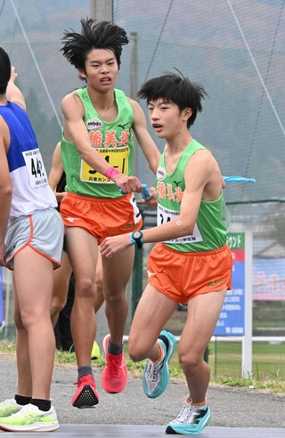 男子・稲美北の１区中川悠聖（左）からたすきを受け、走り出す２区山田遼翔（撮影・大田将之）